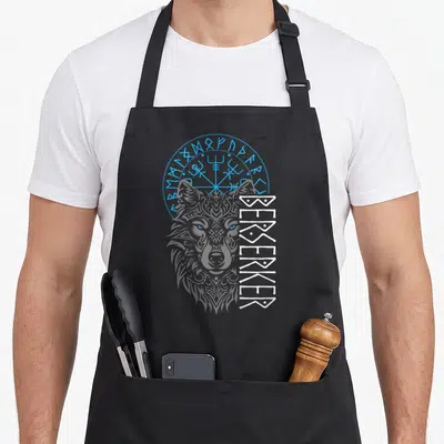 Berserker compass viking apron - Grey wolf head behind blue runic circle with vertical white BERSERKER text in line art — shown on a black cotton canvas apron against a white background