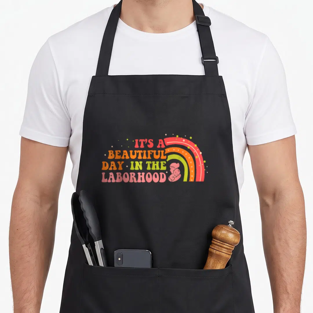 Laborhood beautiful apron - Retro rainbow with stacked text IT'S A BEAUTIFUL DAY IN THE LABORHOOD and silhouette — shown on a black cotton canvas apron against a white background