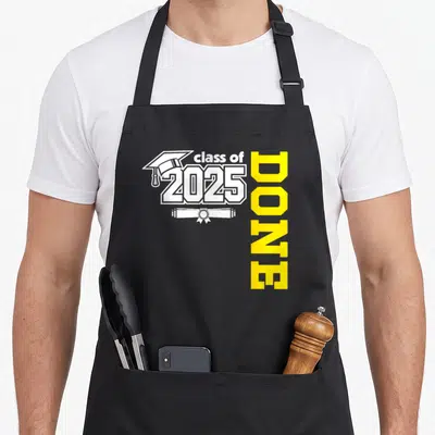 Grad congrat apron - White graduation cap and diploma with class of 2025 text and vertical yellow DONE lettering — shown on a black cotton canvas apron against a white background