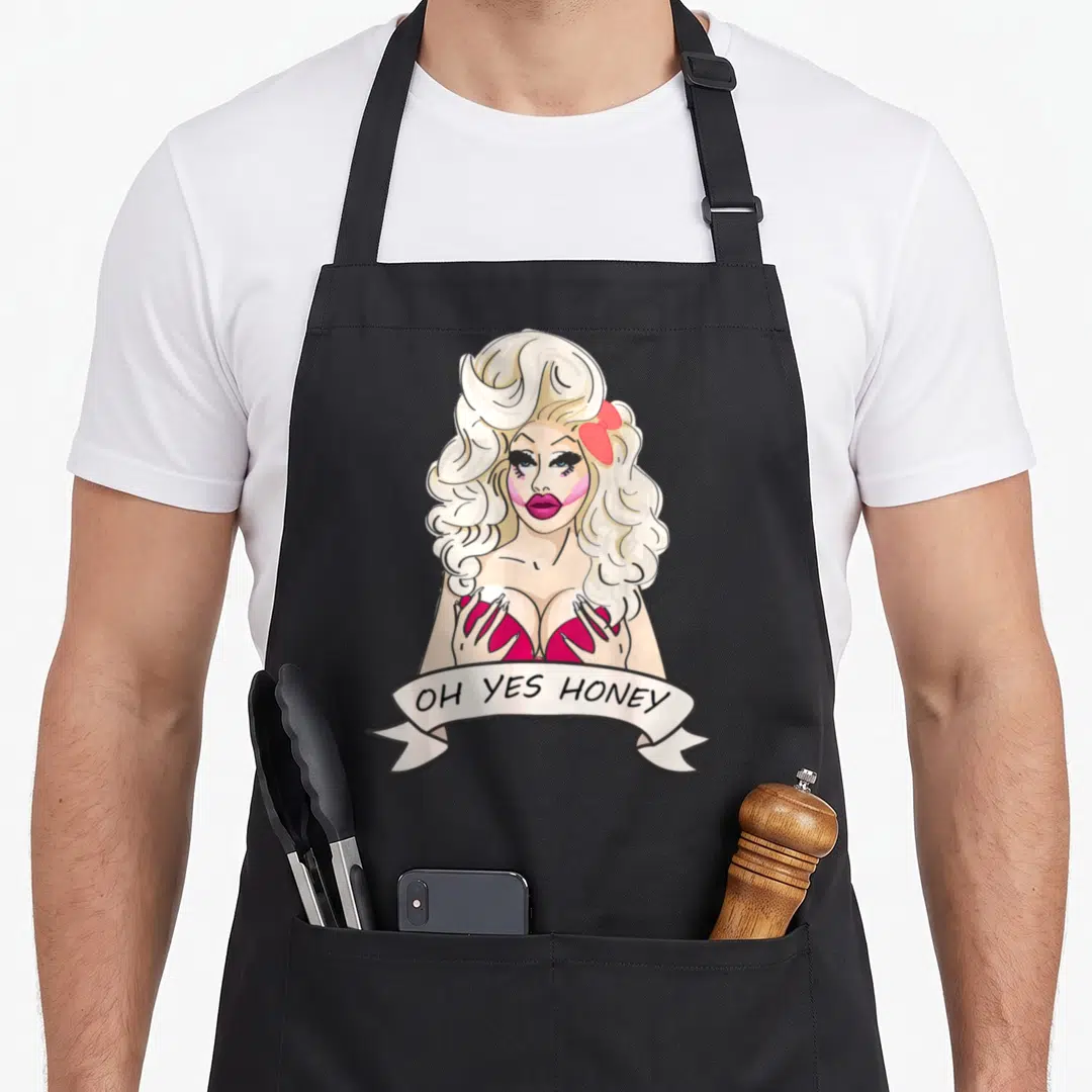 Honey queen apron - Blonde drag queen in red bra with white OH YES HONEY banner — shown on a black cotton canvas apron against a white background