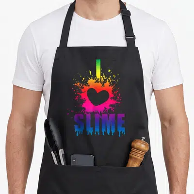 Slime making an apron - Rainbow splatter with pink heart and dripping I Love Slime text — shown on a black cotton canvas apron against a white background