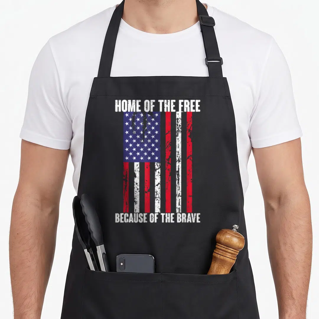 Free american flag apron - Vertical distressed USA flag with Home of the Free Because of the Brave text — shown on a black cotton canvas apron against a white background