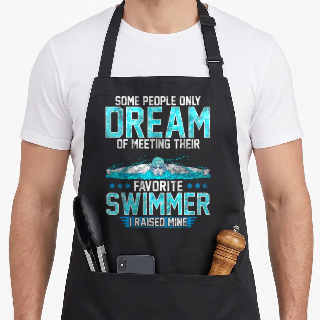 Parent swimming dad apron - Swimmer butterfly stroke graphic with blue water text and proud parent quote — shown on a black cotton canvas apron against a white background