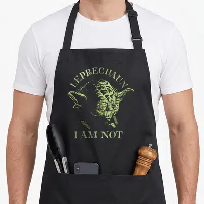 Yoda leprechaun st patrick day aprons - Light green line art of Yoda head with LEPRECHAUN I AM NOT text — shown on a black cotton canvas apron against a white background