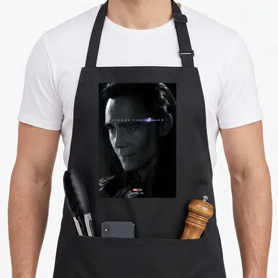 Avenge general apron - Loki face photo AVENGE THE FALLEN text Avengers logo APRIL 26 bottom — shown on a black cotton canvas apron against a white background