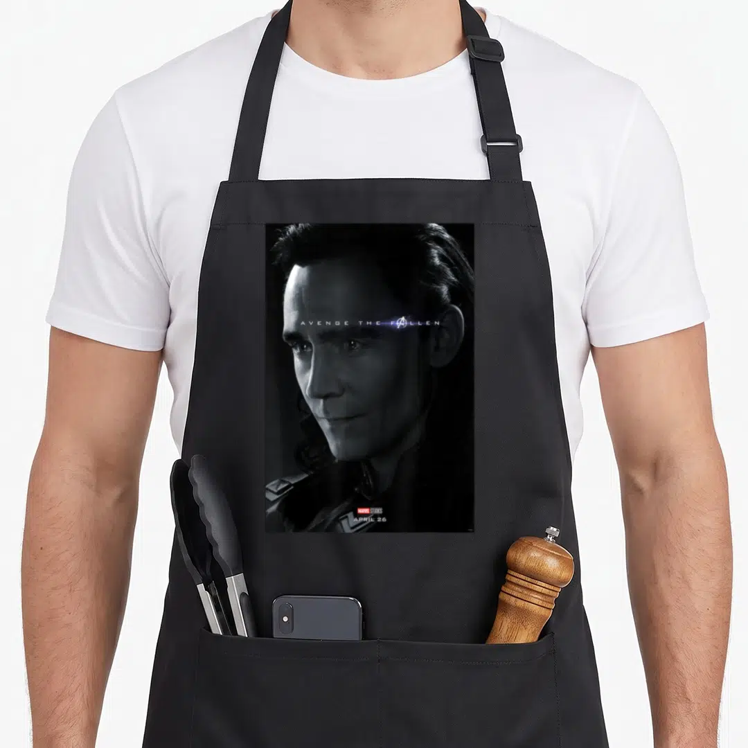 Avenge general apron - Loki face photo AVENGE THE FALLEN text Avengers logo APRIL 26 bottom — shown on a black cotton canvas apron against a white background