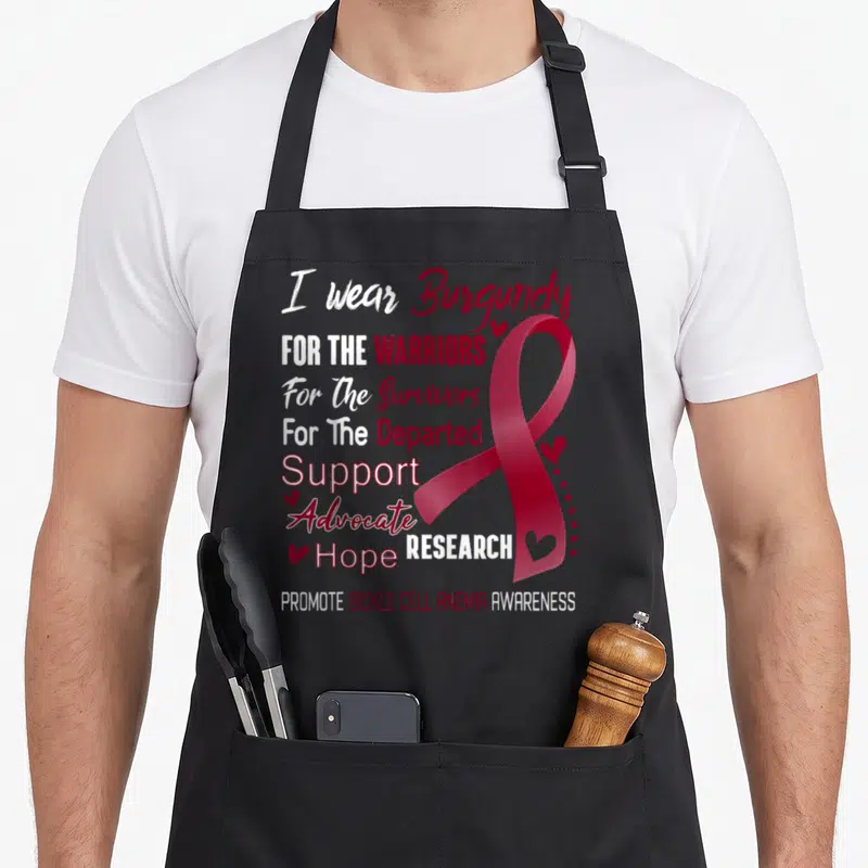 Anemia sickle cell awareness apron - I wear Burgundy text and large burgundy ribbon with small hearts on white — shown on a black cotton canvas apron against a white background
