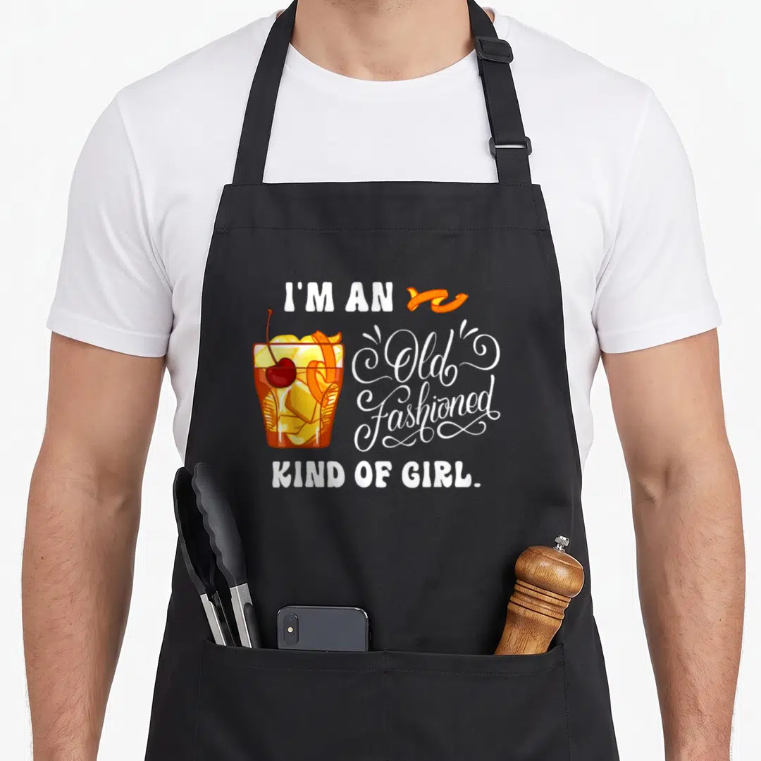 Kind old fashioned aprons - Cartoon cocktail glass with cherry and orange peel next to white text reading I'm An Old — shown on a black cotton canvas apron against a white background