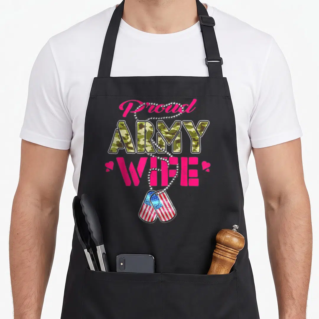 Proud personalized dog apron - Proud Army Wife text with camo fill, silver chain, and US flag dog tags — shown on a black cotton canvas apron against a white background