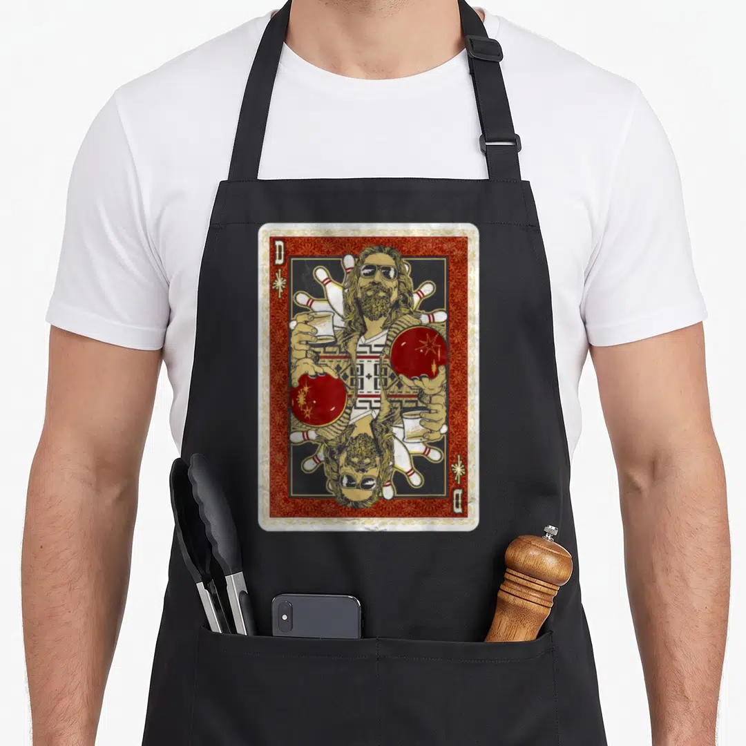 Abide dude apron - Mirrored playing card man holding bowling ball and cup with red gold border and letter B — shown on a black cotton canvas apron against a white background