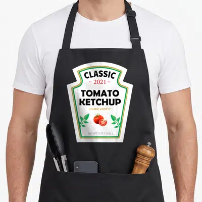 Ketchup diy halloween apron - White label with CLASSIC 2021 TOMATO KETCHUP text and tomato illustration — shown on a black cotton canvas apron against a white background