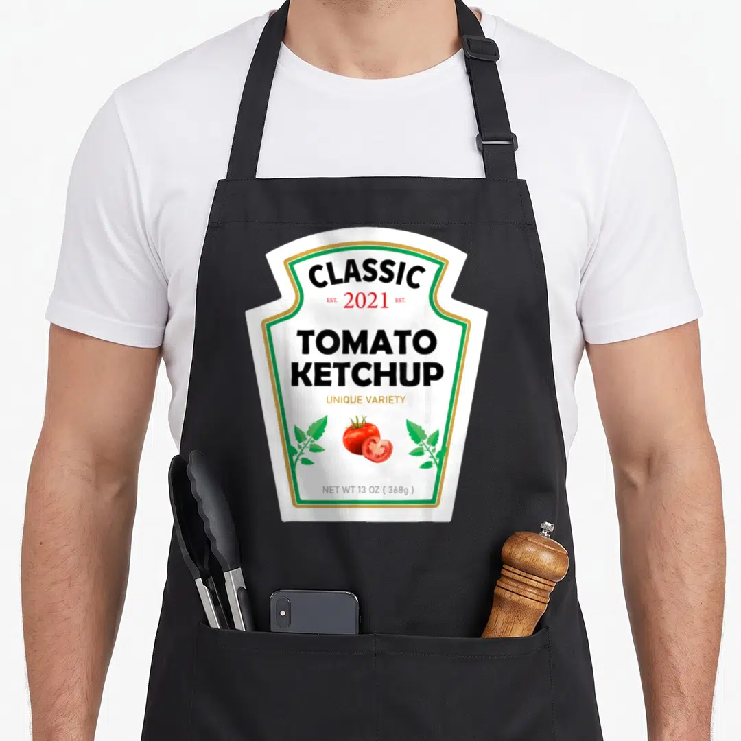 Ketchup diy halloween apron - White label with CLASSIC 2021 TOMATO KETCHUP text and tomato illustration — shown on a black cotton canvas apron against a white background