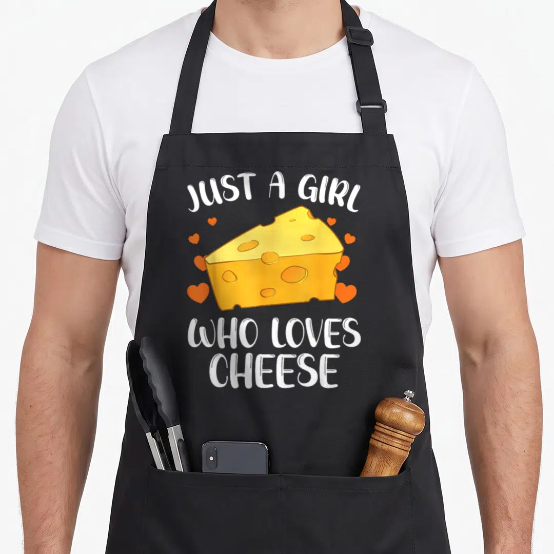 Cheese cottage apron - Cartoon cheese wedge with white text and orange hearts — shown on a black cotton canvas apron against a white background