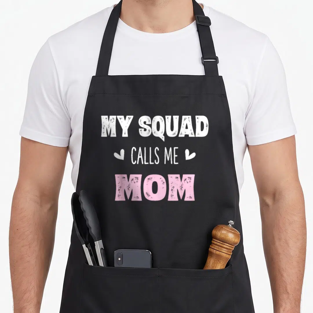Call mama my mother's apron - Stacked text MY SQUAD CALLS ME MOM in white and pink with two small hearts — shown on a black cotton canvas apron against a white background