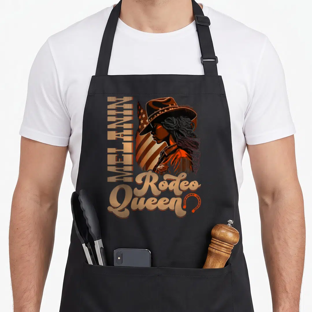 Country african american aprons - Woman in cowboy hat with vertical MELANIN text and Rodeo Queen script in orange brown — shown on a black cotton canvas apron against a white background