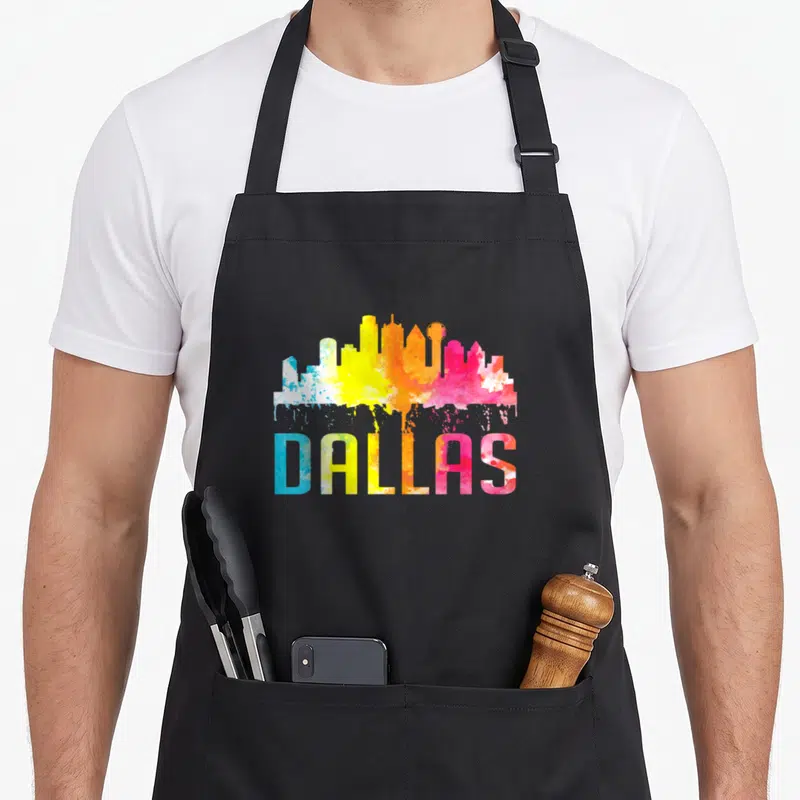 Skyline texas apron - DALLAS text and skyline filled with blue yellow orange pink purple watercolor splash effect — shown on a black cotton canvas apron against a white background