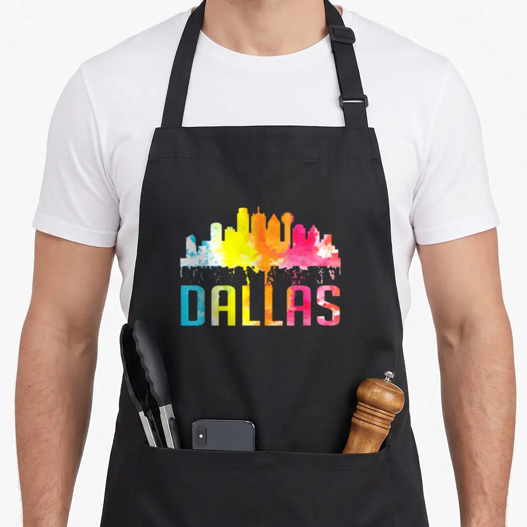 Skyline texas apron - DALLAS text and skyline filled with blue yellow orange pink purple watercolor splash effect — shown on a black cotton canvas apron against a white background