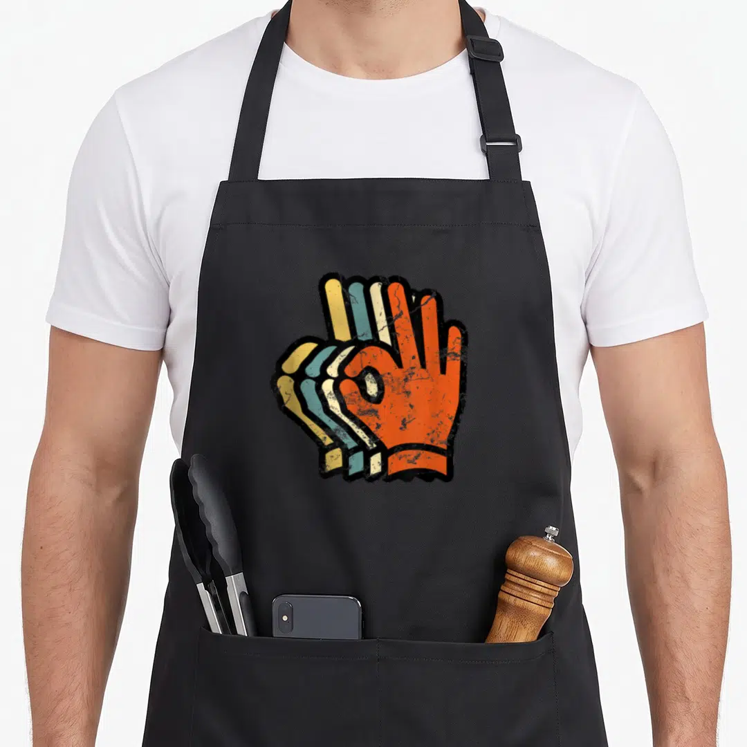 Scuba hand lover apron - Three stacked retro-style hands in OK gesture, colored orange blue yellow black — shown on a black cotton canvas apron against a white background