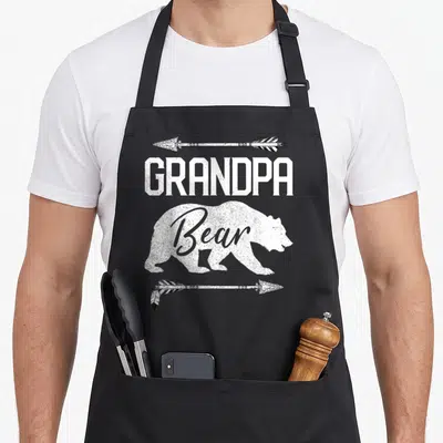 Grandpa bear father day apron - White distressed bear silhouette with GRANDPA text and arrows — shown on a black cotton canvas apron against a white background