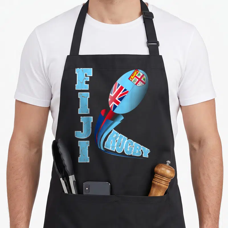Fiji distressed apron - Vertical FIJI text next to a rugby ball wrapped in the Fiji flag with a red and blue swoosh — shown on a black cotton canvas apron against a white background