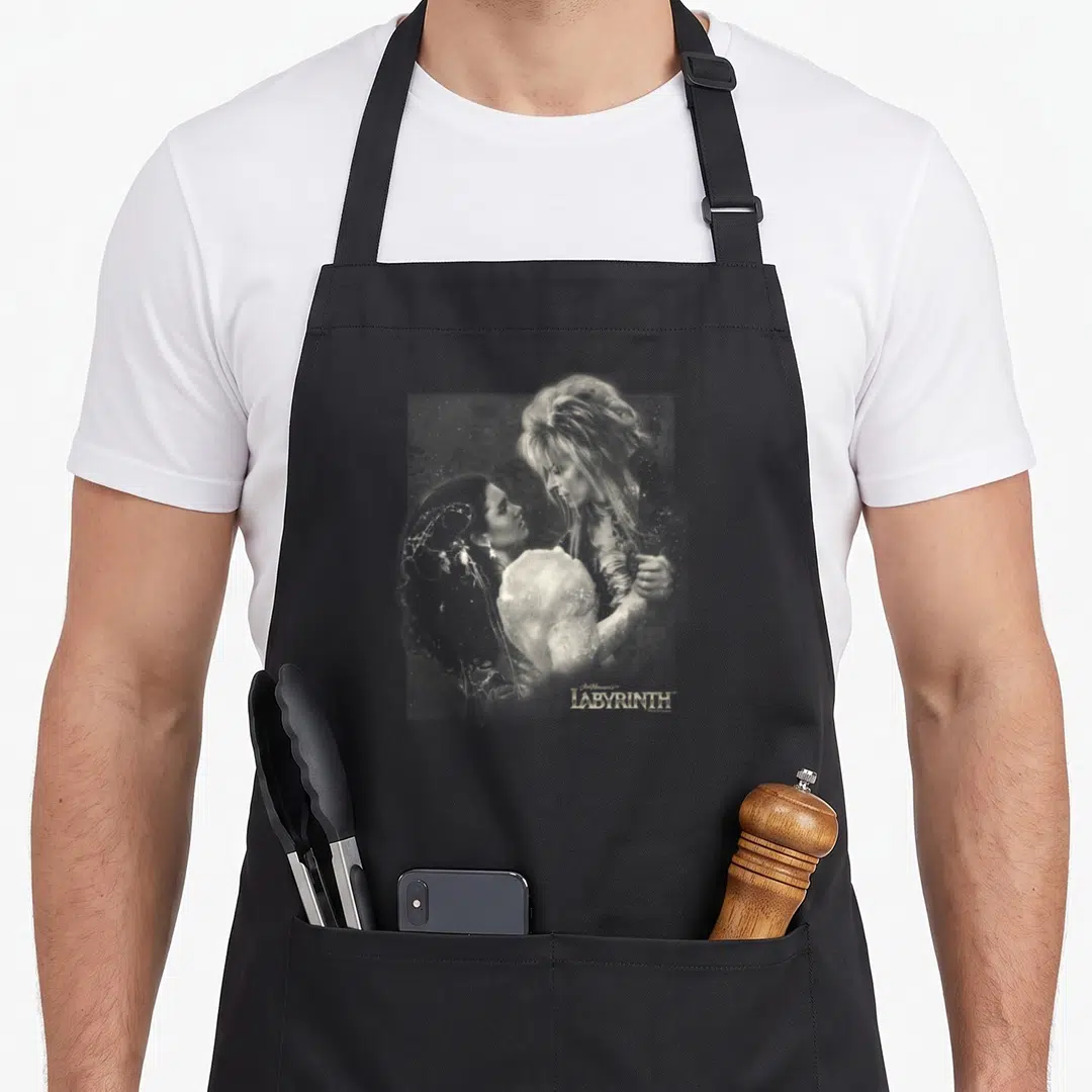 Labyrinth modern apron - Grey and white photo of couple embracing with Jim Henson's LABYRINTH text in gold below — shown on a black cotton canvas apron against a white background
