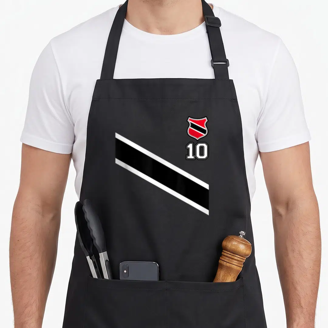 Trinidad football apron - Red and black crest above number 10 with diagonal stripe on black fabric — shown on a black cotton canvas apron against a white background