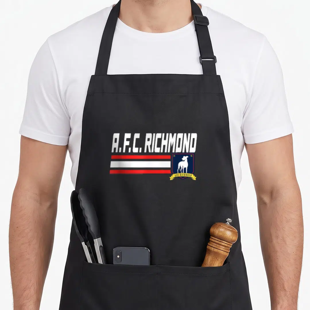 Soccer richmond apron - A.F.C. Richmond text, red stripes, blue shield with white dog, yellow ribbon — shown on a black cotton canvas apron against a white background