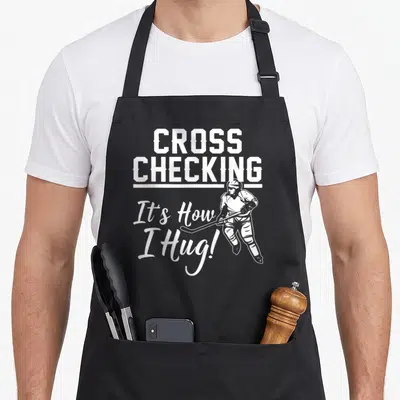 Ice game aprons - White crossed text and hockey player line art on grey background — shown on a black cotton canvas apron against a white background