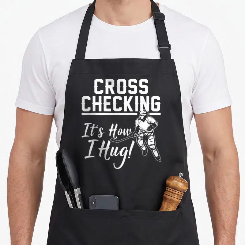 Ice game aprons - White crossed text and hockey player line art on grey background — shown on a black cotton canvas apron against a white background