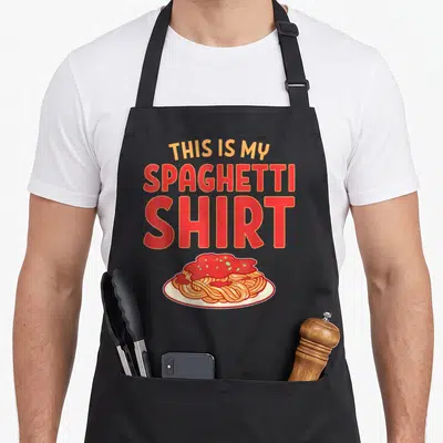 Spaghetti like pasta apron - Cartoon spaghetti plate with red sauce and stacked text reading This Is My Spaghetti Shirt — shown on a black cotton canvas apron against a white background