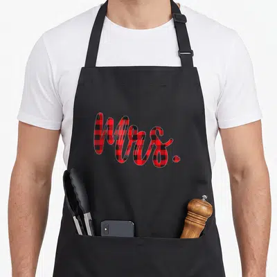 Plaid mr mrs aprons - Mrs. written in cursive filled with red and black buffalo check pattern — shown on a black cotton canvas apron against a white background