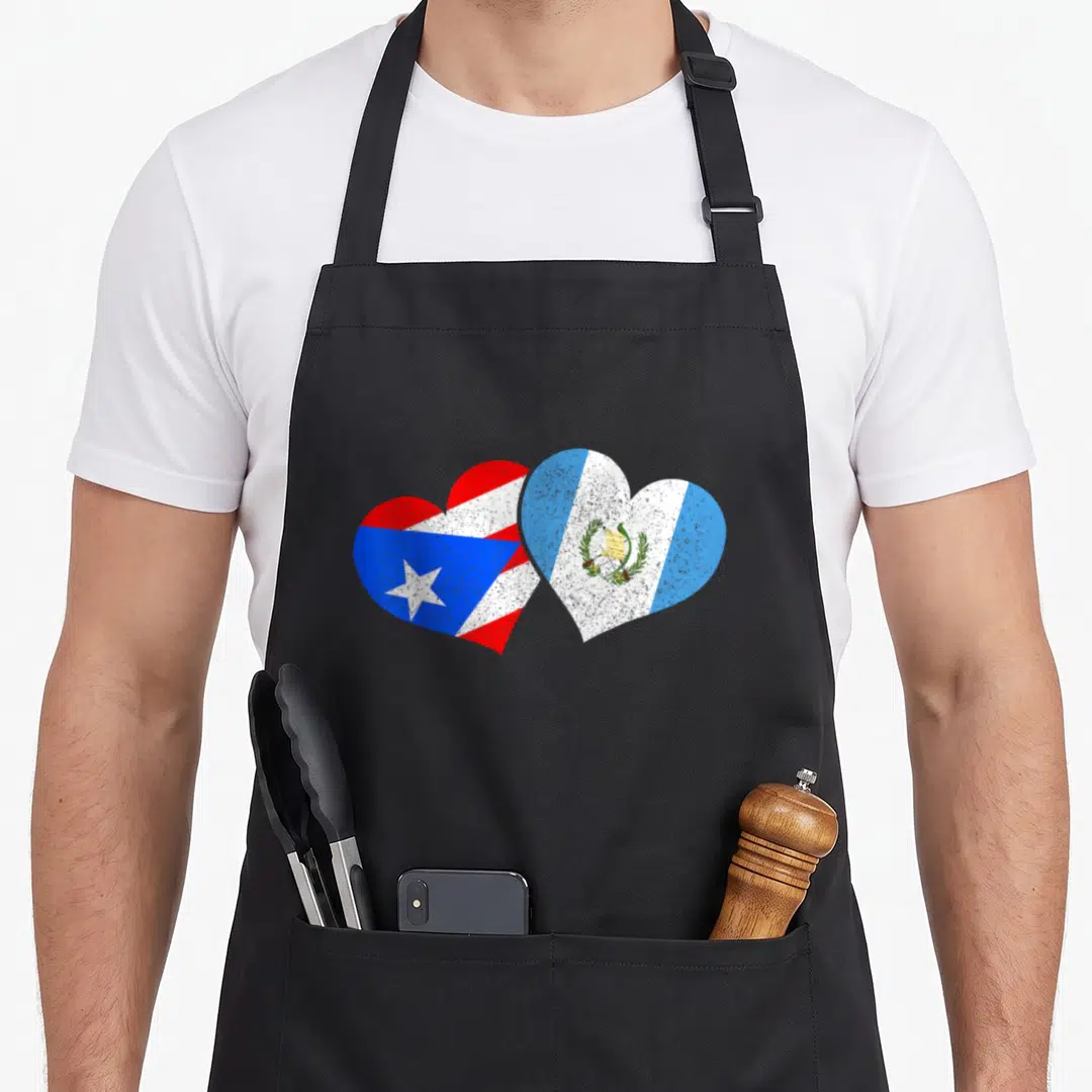 Rico guatemala pride apron - Two hearts side-by-side filled with Puerto Rican and Guatemalan flags in red, white, blue — shown on a black cotton canvas apron against a white background