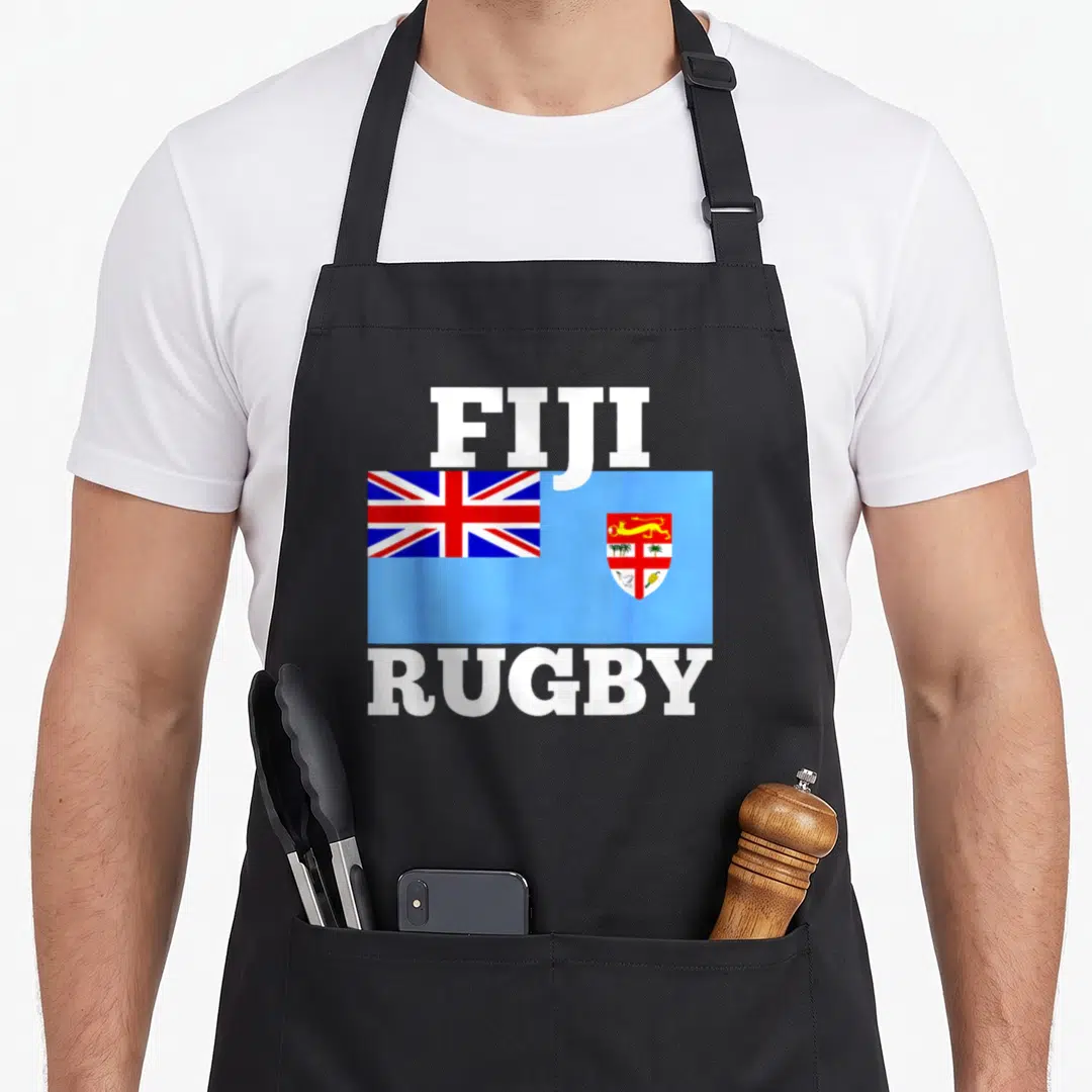 Fiji pride apron - FIJI RUGBY text flanking the flag of Fiji in light blue, white, and red — shown on a black cotton canvas apron against a white background