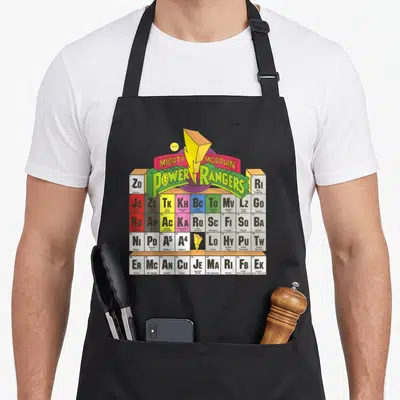 Retro periodic table apron - Mighty Morphin Power Rangers periodic table with character names and yellow lightning bolt — shown on a black cotton canvas apron against a white background