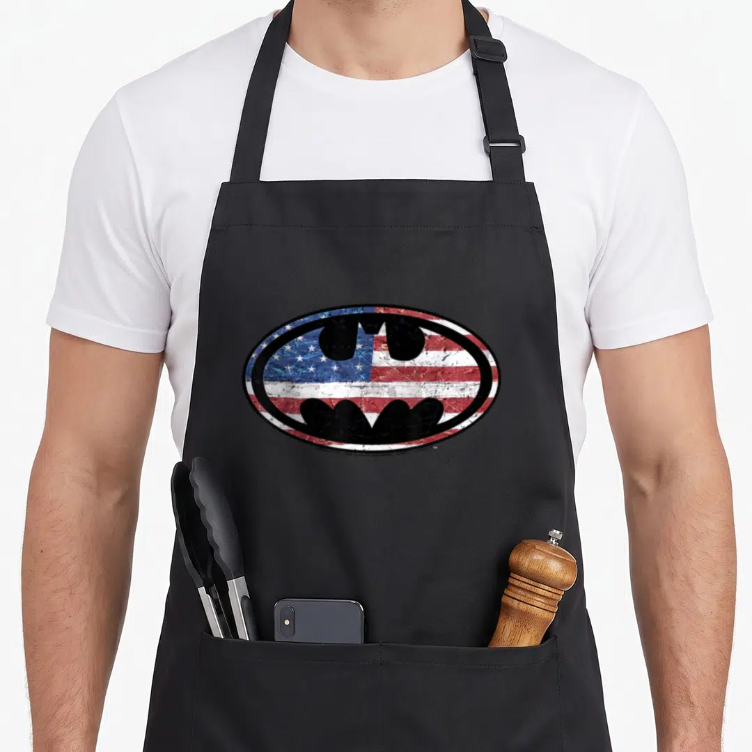 Glory american flag apron - distressed batman logo over oval usa flag in red white and blue — shown on a black cotton canvas apron against a white background