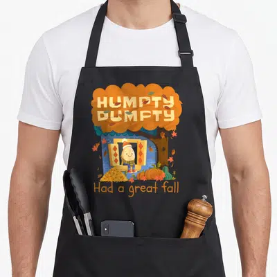 Yall thanksgiving cute fall aprons - Humpty Dumpty egg character in blue house window under orange tree with pumpkins — shown on a black cotton canvas apron against a white background