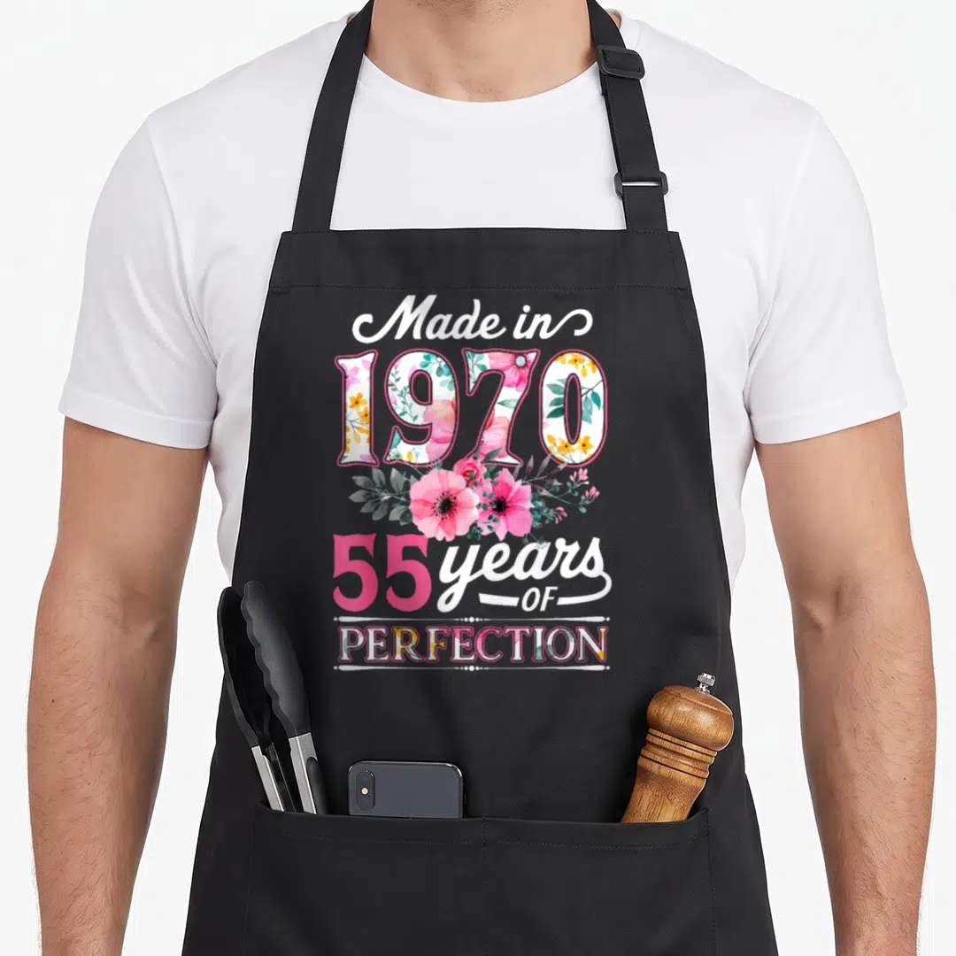 Flower vintage floral apron - Stacked text Made in 1970 55 years OF PERFECTION with pink flowers — shown on a black cotton canvas apron against a white background