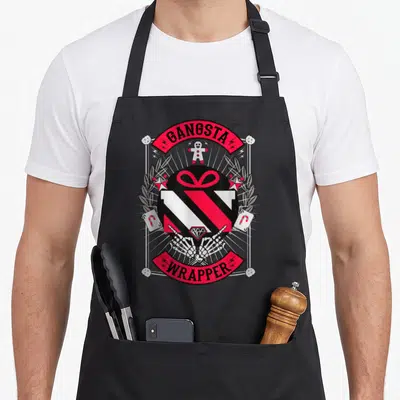 Gangster xmas apron - Cartoon gift box held by skeleton hands with red banners reading GANGSTA WRAPPER — shown on a black cotton canvas apron against a white background