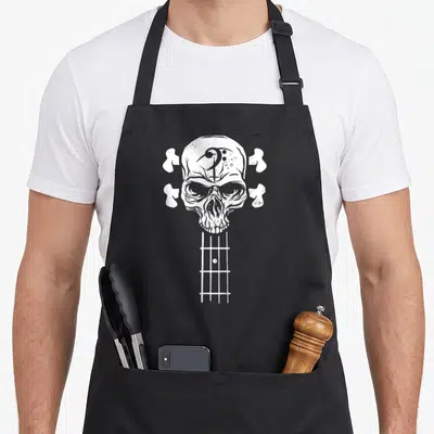 Roll skeleton apron - White distressed skull bass guitar headstock with four bone tuning machines and fretboard — shown on a black cotton canvas apron against a white background
