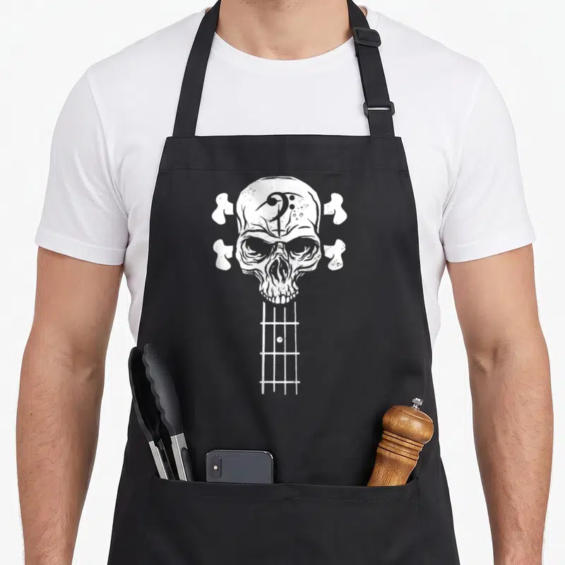 Roll skeleton apron - White distressed skull bass guitar headstock with four bone tuning machines and fretboard — shown on a black cotton canvas apron against a white background