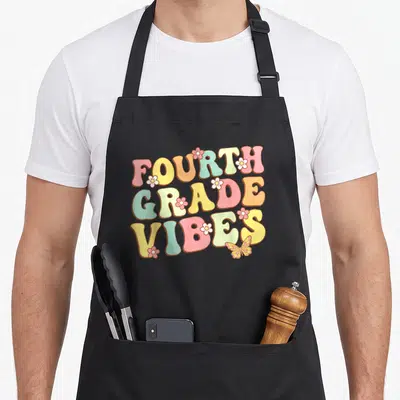 Fourth grade hello teacher apron - Retro text reading FOURTH GRADE VIBES in pastel colors with small flowers — shown on a black cotton canvas apron against a white background