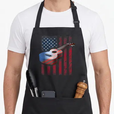 Acoustic american flag apron - Ukulele with red white blue flag pattern on distressed background — shown on a black cotton canvas apron against a white background