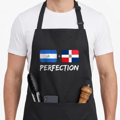 Perfection flag heritage aprons - Two flags with plus sign and word PERFECTION in blue white red — shown on a black cotton canvas apron against a white background