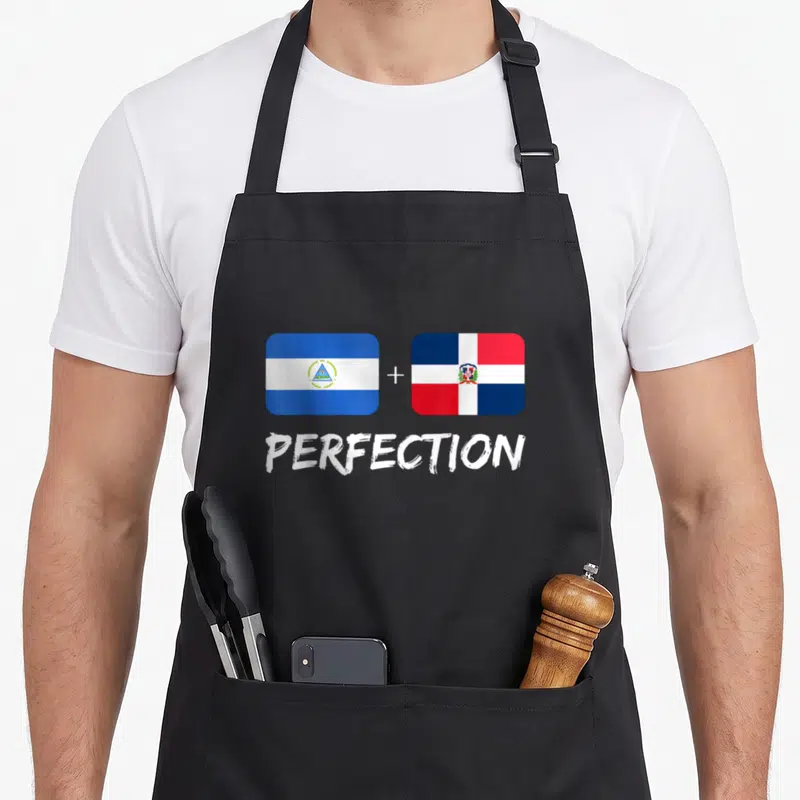 Perfection flag heritage aprons - Two flags with plus sign and word PERFECTION in blue white red — shown on a black cotton canvas apron against a white background