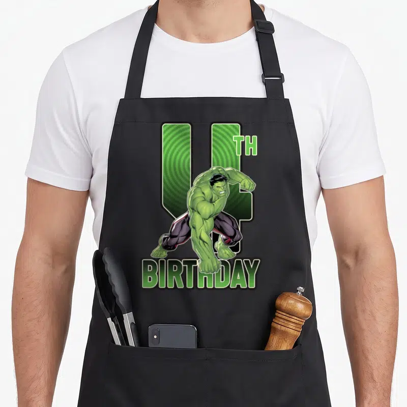 4th birthday apron - Hulk crouching in front of green number 4 with TH BIRTHDAY text below — shown on a black cotton canvas apron against a white background