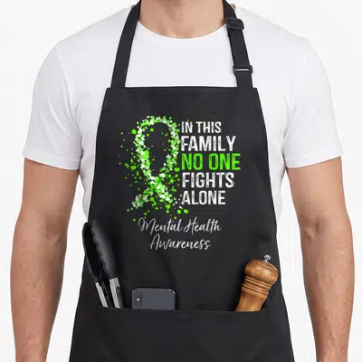 Mental family aprons - Lime green and white scattered heart awareness ribbon with distressed stacked text reading — shown on a black cotton canvas apron against a white background