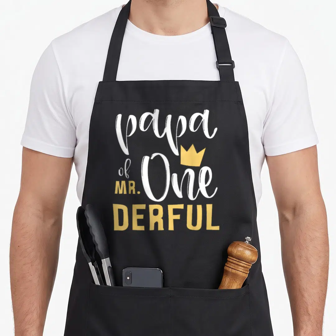 Papa birthday apron - Stacked white and yellow text reading papa of One MR. DERFUL with a small gold crown — shown on a black cotton canvas apron against a white background