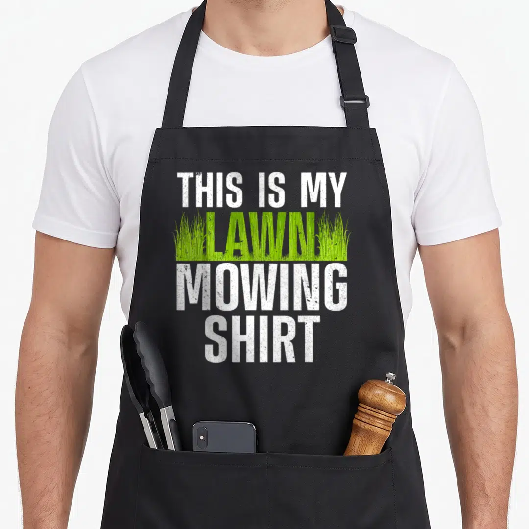 Groundskeeper landscaper apron - Stacked text THIS IS MY LAWN MOWING SHIRT with green grass blades filling the middle — shown on a black cotton canvas apron against a white background