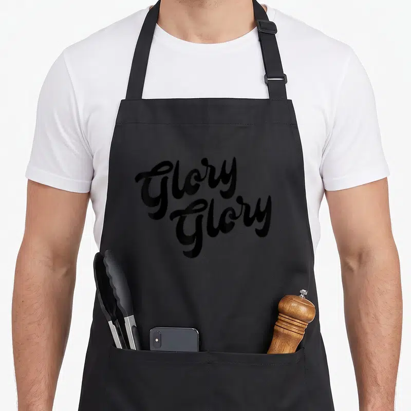Glory rally apron - Stacked black cursive text reading Glory Glory on plain background — shown on a black cotton canvas apron against a white background