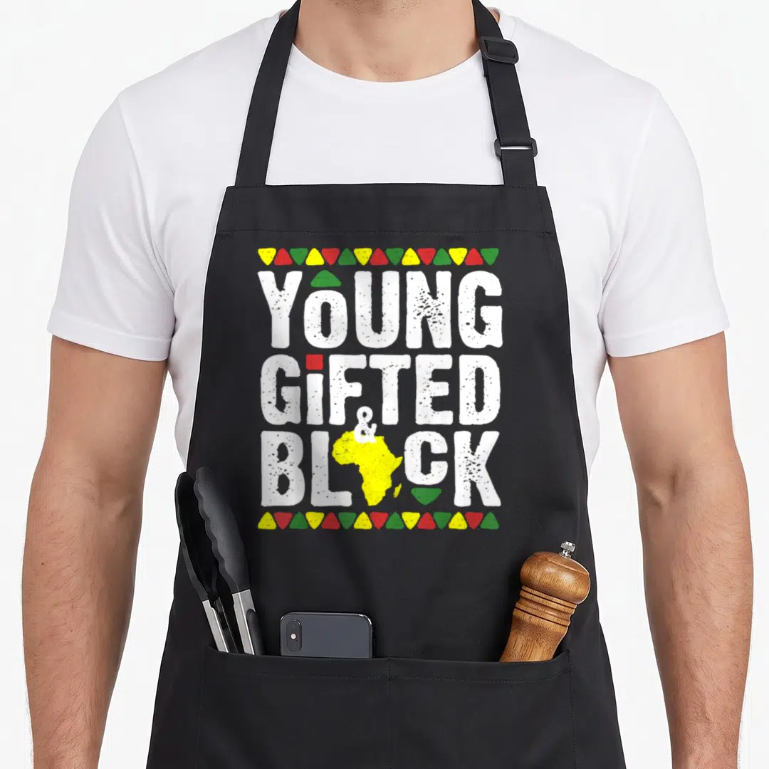Gifted magic apron - Young Gifted & Block text with yellow Africa map and colored triangle borders — shown on a black cotton canvas apron against a white background